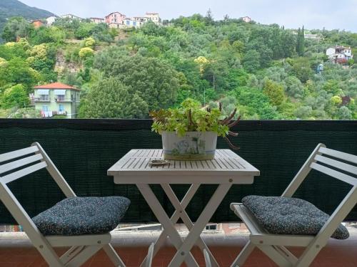 斯培西亚Decò & Retrò apartment的阳台上摆放着两把椅子和一张桌子,上面放着盆子