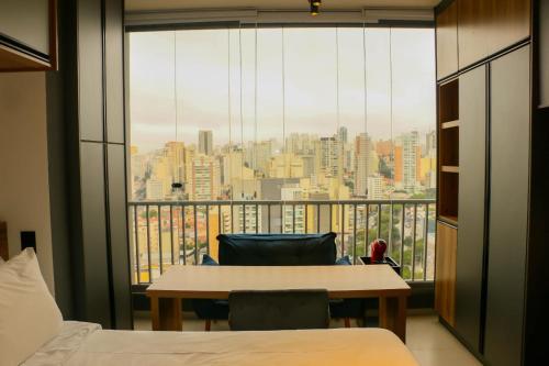 圣保罗Belíssimo Stúdio的客房设有带桌椅的大窗户。