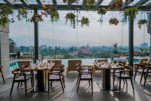 加德满都Hotel Barahi Kathmandu的餐厅设有桌椅和大窗户。