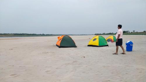 AuraiyaJhoomke camping and water sports adventure的一个人在海滩上行走,有三个帐篷