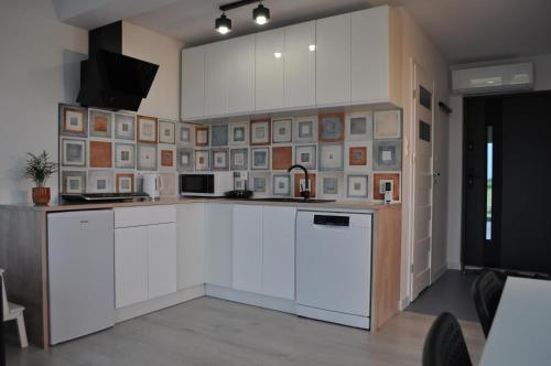 达尔沃沃Apartament 4 Pory Roku的厨房配有白色橱柜和一堵画墙