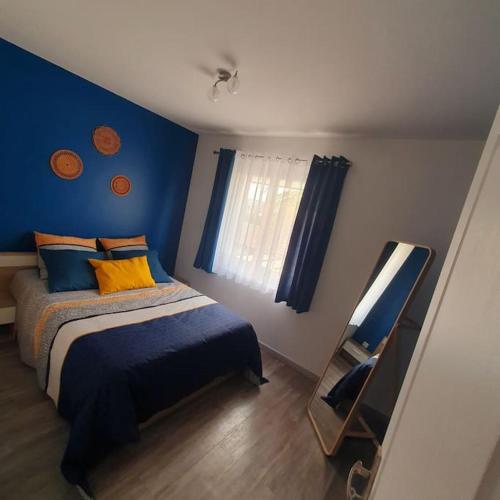 马里尼亚讷Joli haut de villa 3 chambres climatisé avec jacuzzi的一间卧室设有一张床和蓝色的墙壁