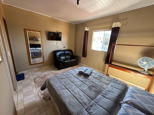 戈亚斯州上帕莱索Flats Paraíso Dos Ipês的一间卧室配有一张床和一张皮椅