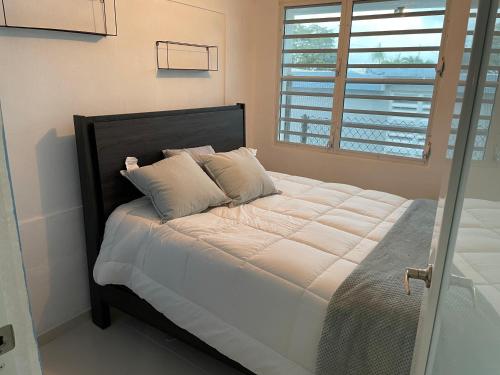 卢基约Luquillo Mar Paradise的卧室内的一张带白色床单和枕头的床