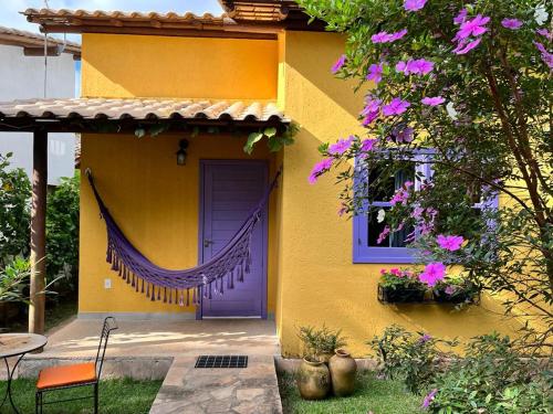 伦索伊斯Chalés Calima的黄色的房子,有紫色的门和窗户