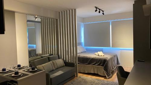 库里提巴Studio LifeSpace Batel Curitiba的一间卧室配有一张床、一张沙发和一面镜子