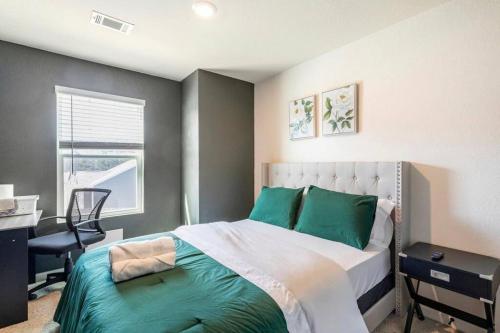 亚特兰大Modern Retreat near Hartsfield-Jackson Airport的一间卧室配有一张带绿色枕头的床和一张书桌