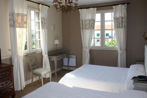 滨海苏拉克Hotel des Pins的一间卧室配有一张床、一张书桌和两个窗户。