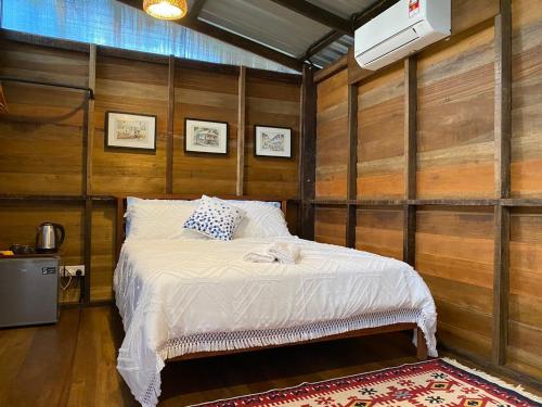 温泉村Kebun Lisdtari farmstay的卧室配有一张床铺,位于带木墙的房间内