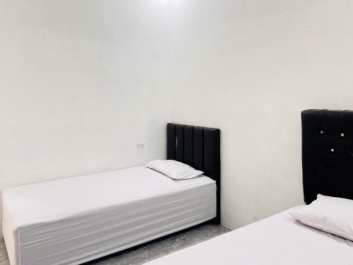 BinjaiRedDoorz Syariah @ Binjai Timur的白色墙壁客房的两张床