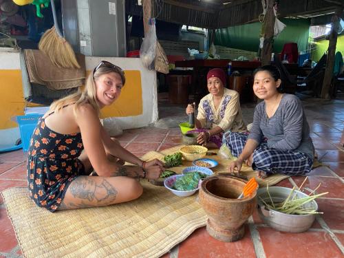 Phumĭ Poŭthĭ Mâ SreiLazy Mango Home Stay的一群坐在地板上吃食物的三个女人