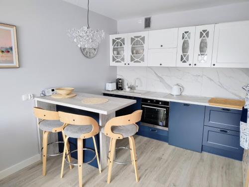库瑞尼卡慕斯卡Luksusowy Apartament Stella - Port Krynica Morska的厨房配有蓝色橱柜和带凳子的台面