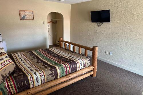 默多Love Hotels Murdo on Interstate 90的一间卧室配有一张木床,墙上配有电视
