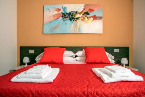 维罗纳Camelot Red - Appartamenti的一张红色的床,配有两个红色枕头和绘画