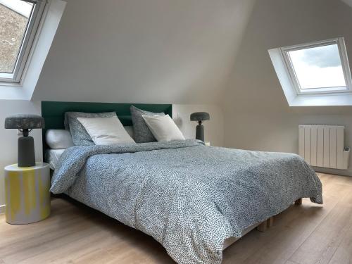 孔卡尔诺Au Troisieme的一间卧室配有一张带灰色毯子的床和两个窗户