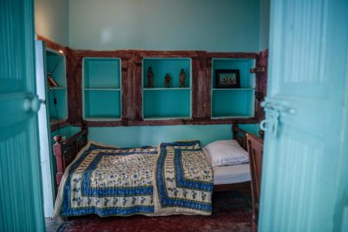 焦特布尔Bristows Haveli Homestay的一间卧室配有一张带蓝色墙壁和架子的床
