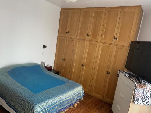 讷伊-普莱桑斯Belle chambre spacieuse的一间卧室配有木制橱柜、一张床和一台电视机。