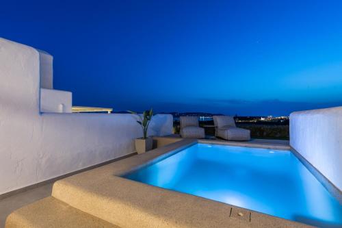 帕罗斯岛Sersi Paros Villas & Suites的蓝色灯光的房子里的一个游泳池