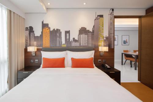 马尼拉Citadines Benavidez Makati的一间卧室配有一张带橙色枕头的大床