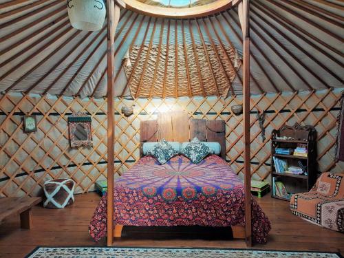 佩内拉Green Man yurt的蒙古包内一间卧室,配有一张天蓬床
