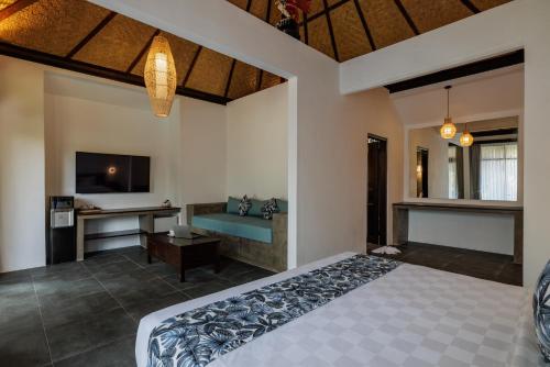 乌布乌布得达利酒店的一间卧室配有一张床、一张书桌和一台电视