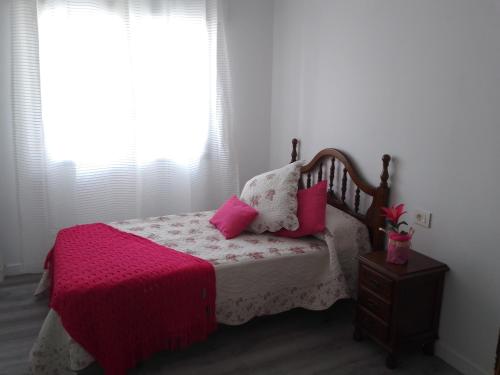 格罗韦Aires do mar的一间卧室配有带粉红色枕头的床和窗户。