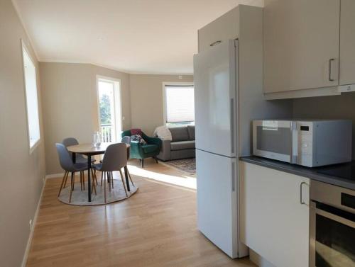 阿伦达尔Cozy and new apartment in Arendal -Hill的厨房配有桌子和白色冰箱。