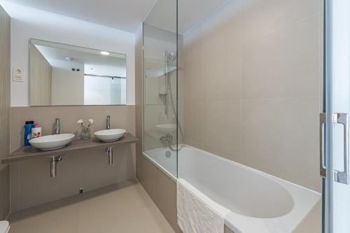 贝纳尔马德纳3 Bedroom sea view Stupa Hills的带浴缸、两个盥洗盆和淋浴的浴室。