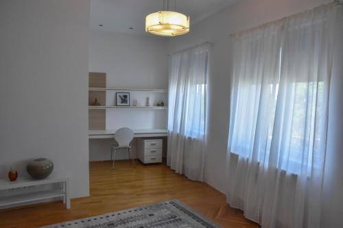 维斯普雷姆Furmint & Juhfark Apartmanok的白色的客房设有窗帘、书桌和窗户。