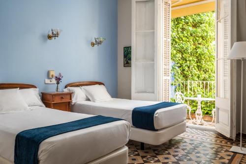 锡切斯雷纳新卡媒介酒店的带窗户的客房内的两张床
