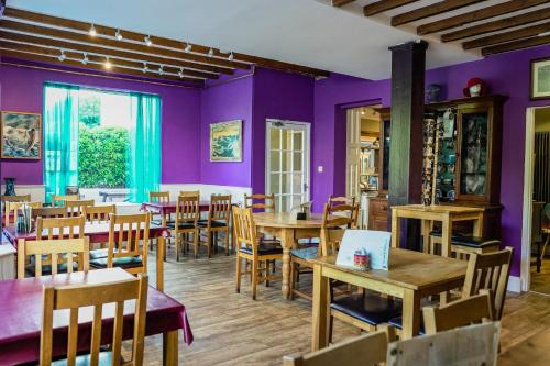 滕比Manorbier House - Lundy North Room的餐厅拥有紫色的墙壁和木桌及椅子