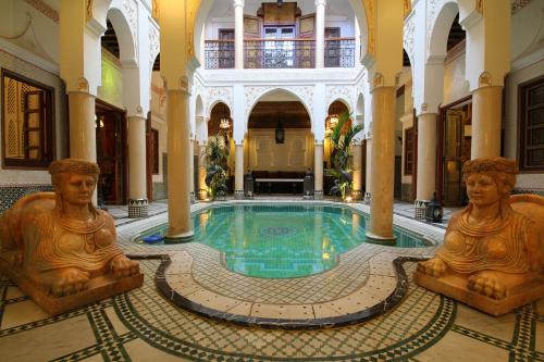 马拉喀什Riad Esmeralda的一座有雕像环绕的建筑中的游泳池