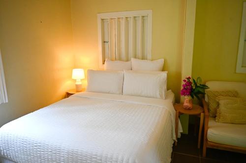 飞鱼湾Rumah Biru的卧室配有一张白色大床和一把椅子