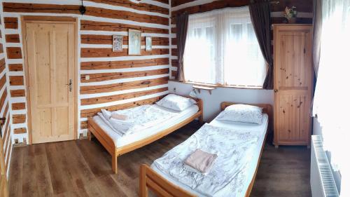 RudníkWellness chata - Krkonoše的配有木墙和窗户的客房内的两张床