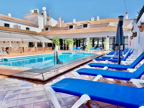 奥尔维拉Hotel Tugasa Sierra y Cal的一座带蓝色躺椅的游泳池以及一座建筑