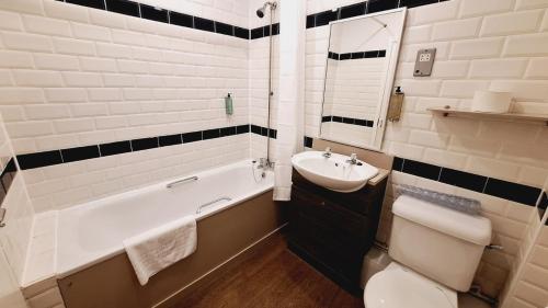 威根The Brocket Arms Wetherspoon的浴室配有盥洗盆、卫生间和浴缸。