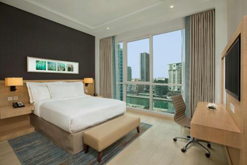 迪拜迪拜朱美拉海滩希尔顿逸林酒店的配有一张床、一张书桌和一扇窗户的酒店客房
