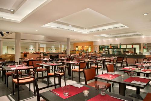 菲乌米奇诺罗马机场花园客栈酒店的餐厅配有桌椅和红色餐巾