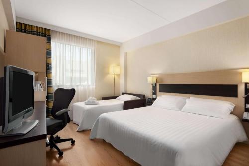 菲乌米奇诺罗马机场花园客栈酒店的酒店客房设有两张床和一台平面电视。