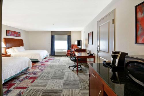 格尔夫波特格尔夫波特希尔顿花园酒店比洛克西机场店的酒店客房设有两张床、一张桌子和一台电视。