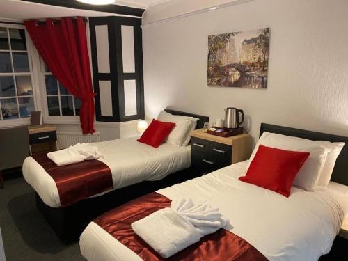 TitchfieldThe Bugle Hotel的酒店客房 - 带两张带红色枕头的床