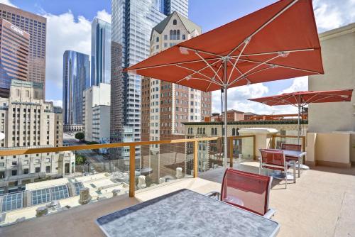 洛杉矶洛杉矶希尔顿切克斯酒店的阳台配有桌椅和遮阳伞。