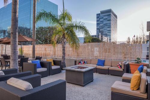 埃尔塞贡多LAX希尔顿逸林酒店-埃尔塞贡多的一个带沙发和桌子及棕榈树的庭院