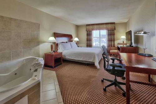 拉斯克鲁塞斯拉斯克鲁塞斯希尔顿花园酒店的酒店客房配有一张床、一张书桌和一个浴缸。