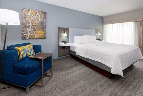 堪萨斯城乡村俱乐部广场汉普顿套房酒店的酒店客房,配有一张床和一张蓝色椅子