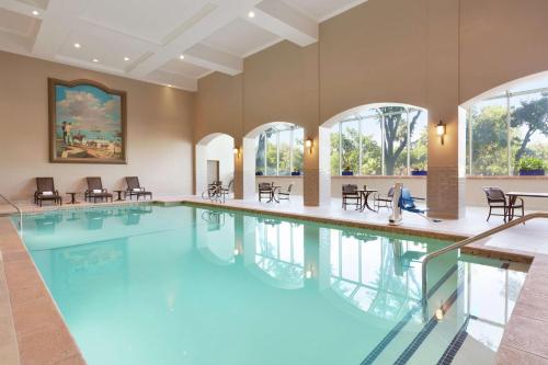 米尔皮塔斯Embassy Suites by Hilton Milpitas Silicon Valley的一个带桌椅和窗户的大型游泳池