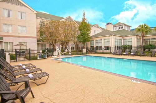 肯纳新奥尔良机场希尔顿花园酒店的一座带椅子的游泳池以及一座建筑