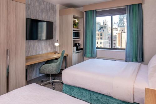 纽约纽约/曼哈顿切尔西希尔顿花园酒店的酒店客房设有两张床、一张书桌和一个窗户。