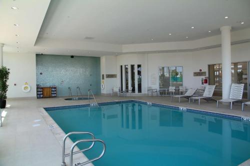安大略安大略省大使馆套房酒店 - 机场的一个带椅子和桌子的大型游泳池