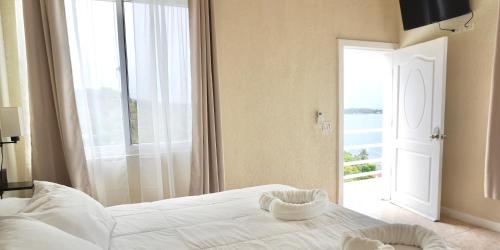 罗阿坦Ocean View Hotel and Restaurant的卧室设有白色的床和大窗户